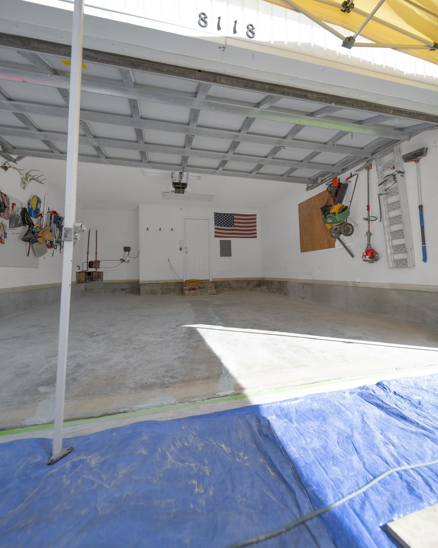 Bare garage slab seen from the driveway with the canopy up and the floor masked for preparation