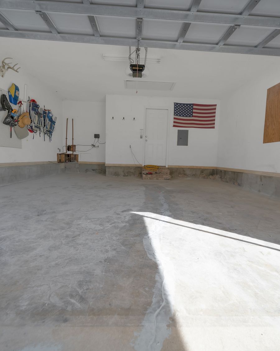 Bare concrete garage slab masked off with tarps before any grinding or coating