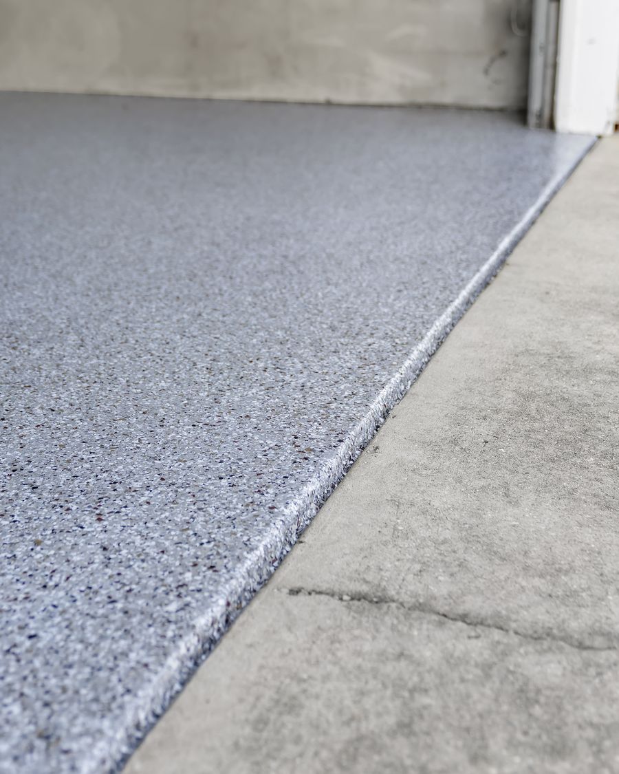 The coated floor stopping in a clean line at the garage threshold, next to the bare driveway
