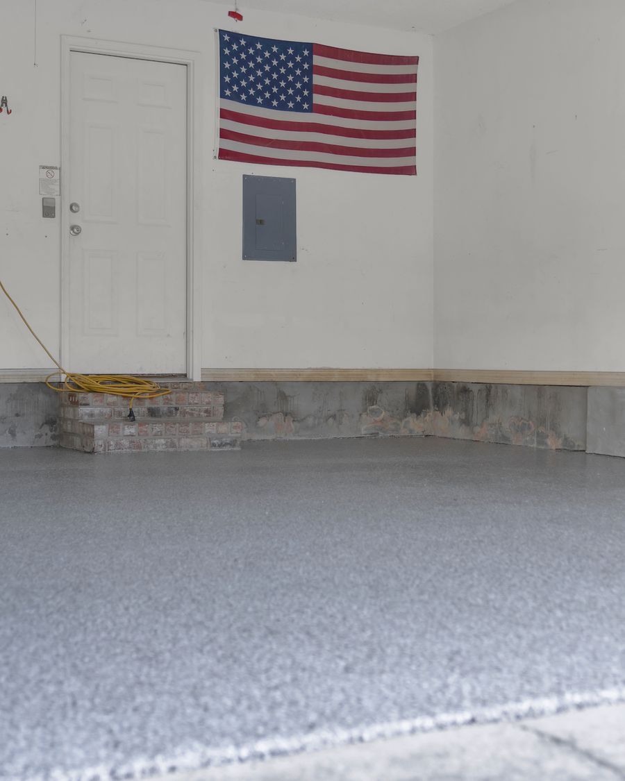 Finished grey and white chip flake floor running up to the back wall of the garage