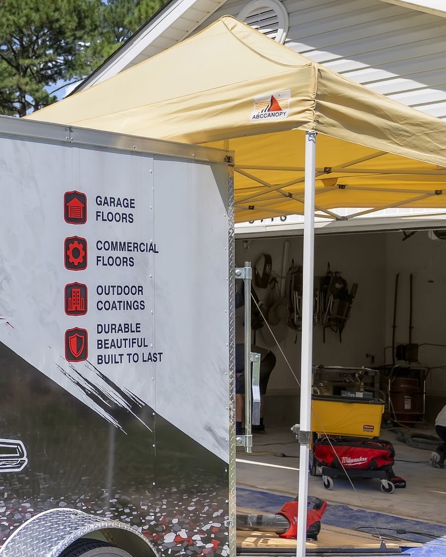 The Rescue 1 Epoxy trailer and canopy set up at the open garage door on a job